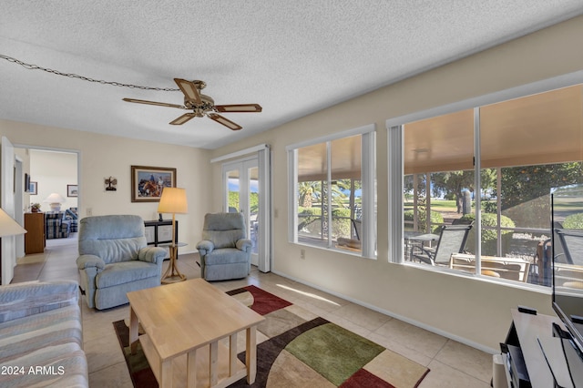 living room featuring ceiling fan, a healthy amount of sunlight, light tile patterned floors, and a textured ceiling