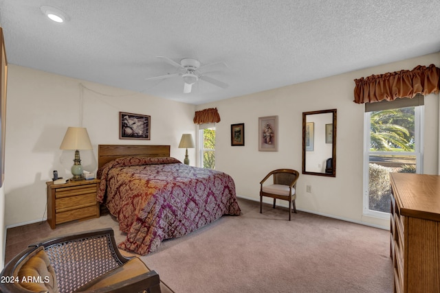 carpeted bedroom featuring ceiling fan and a textured ceiling