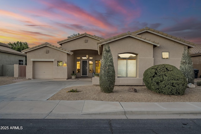 mediterranean / spanish home with a tile roof, driveway, an attached garage, and stucco siding