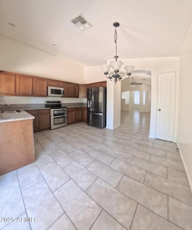 22951 W Loma Linda Blvd, Buckeye, AZ 85326 - kitchen featuring appliances with stainless steel finishes, a chandelier, ceiling fan, brown cabinets, and light tile patterned floors