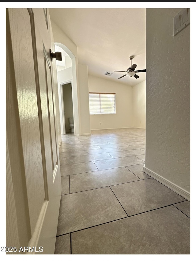 22951 W Loma Linda Blvd, Buckeye, AZ 85326 - hallway featuring arched walkways, lofted ceiling, a textured wall, and tile patterned floors