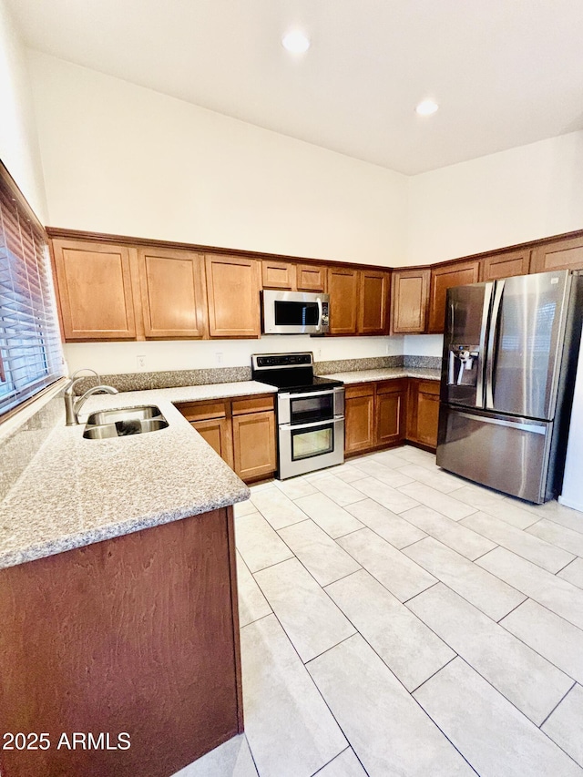 22951 W Loma Linda Blvd, Buckeye, AZ 85326 - kitchen with stainless steel appliances, light tile patterned floors, brown cabinetry, light stone countertops, and recessed lighting