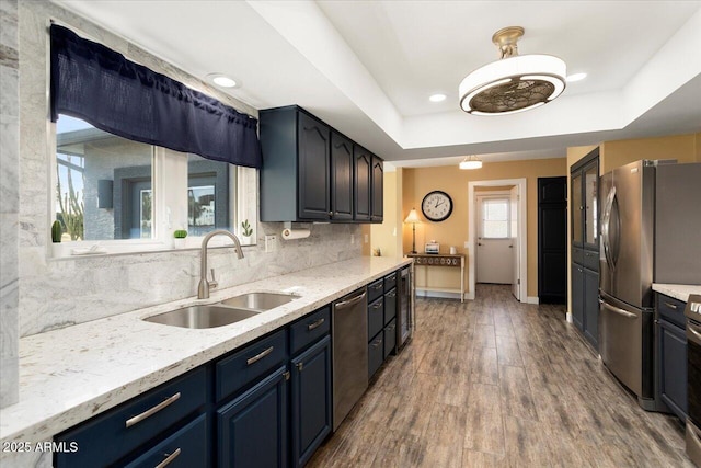 kitchen featuring blue cabinetry, sink, appliances with stainless steel finishes, a raised ceiling, and decorative backsplash