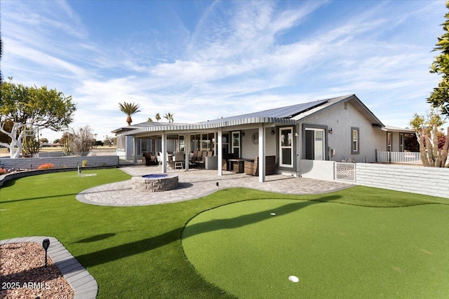 rear view of property featuring a patio, a fire pit, and solar panels