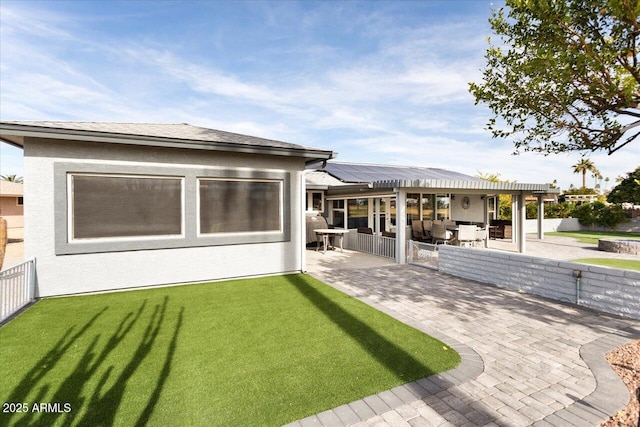 back of house featuring a yard, a patio, and solar panels