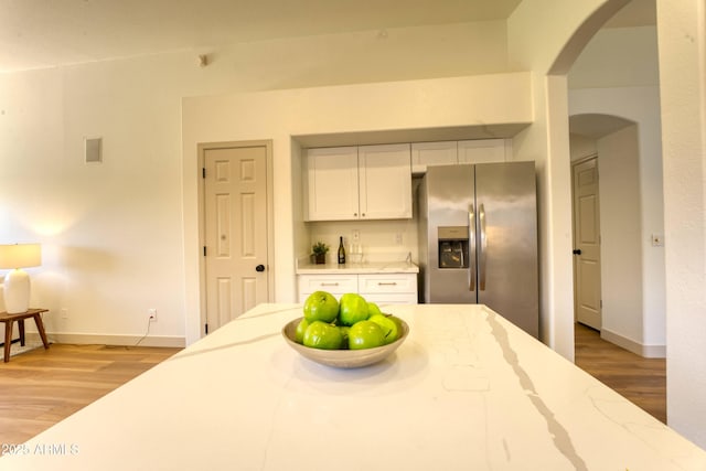3940 E Heather Ct, Gilbert, AZ 85234 - kitchen with stainless steel fridge, arched walkways, light wood-type flooring, white cabinets, and light stone countertops