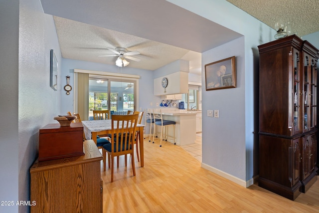 dining space featuring ceiling fan, light hardwood / wood-style floors, and a textured ceiling