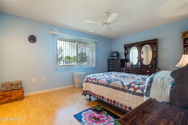 bedroom featuring ceiling fan, light hardwood / wood-style flooring, and a textured ceiling