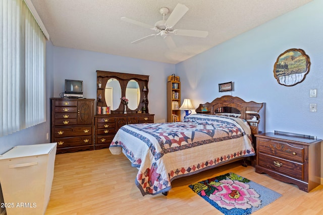 bedroom with ceiling fan, a textured ceiling, and light hardwood / wood-style floors