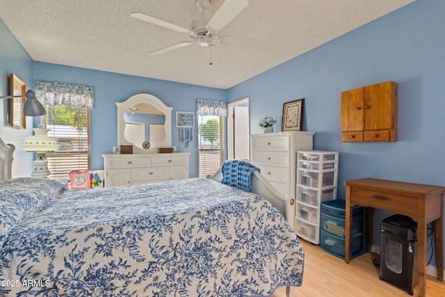 bedroom with ceiling fan, a textured ceiling, and light wood-type flooring