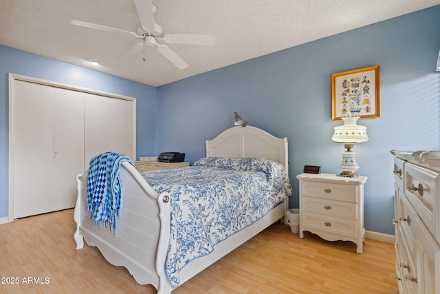 bedroom with ceiling fan, light hardwood / wood-style floors, a closet, and a textured ceiling