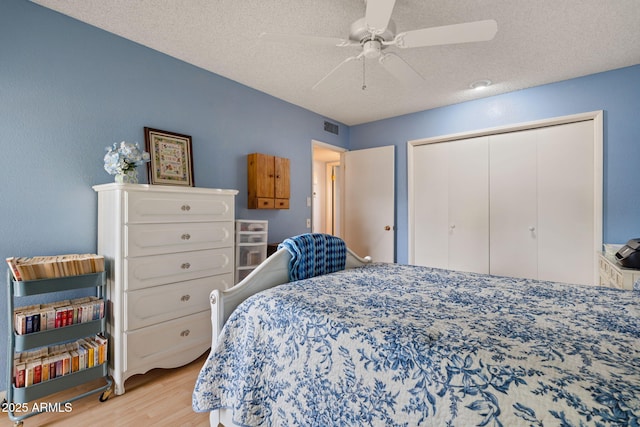 bedroom with a closet, ceiling fan, a textured ceiling, and light hardwood / wood-style flooring