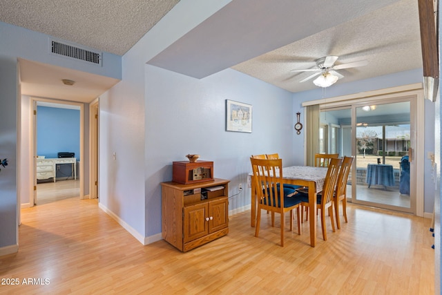 dining room featuring ceiling fan, light hardwood / wood-style flooring, and a textured ceiling