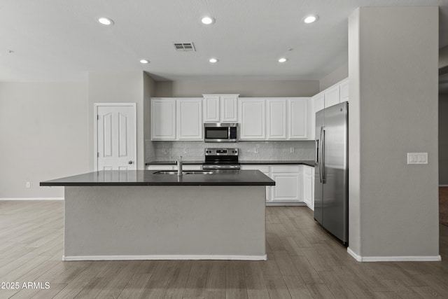 29302 N 126th Ln, Peoria, AZ 85383 - kitchen featuring stainless steel appliances, a sink, dark countertops, backsplash, and light wood finished floors