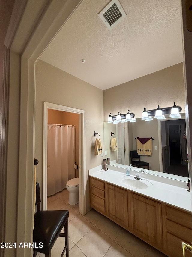 bathroom featuring tile patterned floors, vanity, a textured ceiling, and toilet