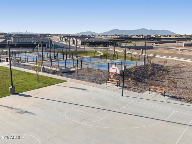 view of home's community with a mountain view, fence, community basketball court, and a tennis court
