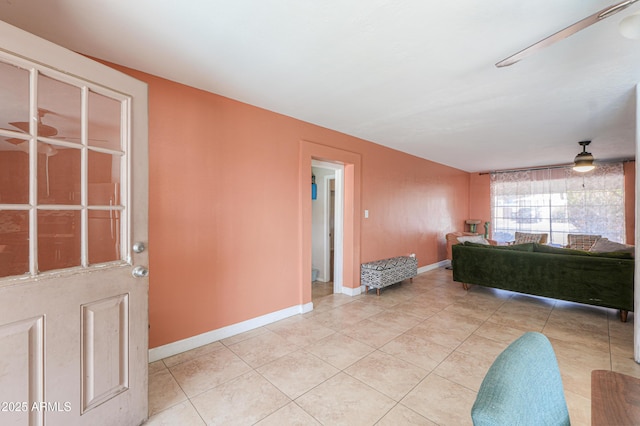 living area featuring a ceiling fan, light tile patterned floors, and baseboards