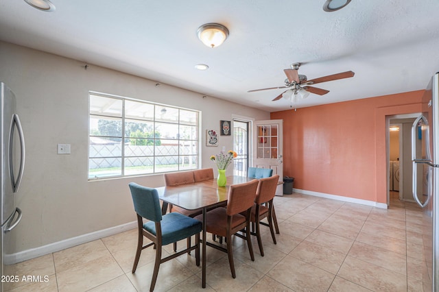 dining room featuring a ceiling fan, light tile patterned floors, washer / dryer, and baseboards