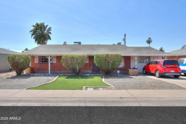 ranch-style home featuring a front lawn, a shingled roof, brick siding, and concrete driveway
