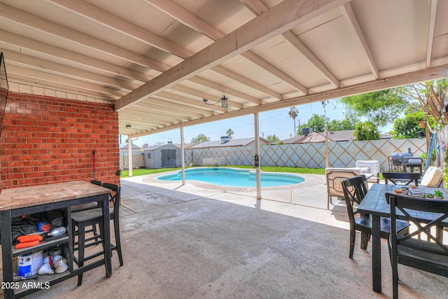 view of swimming pool with a storage unit, a fenced backyard, and a patio area