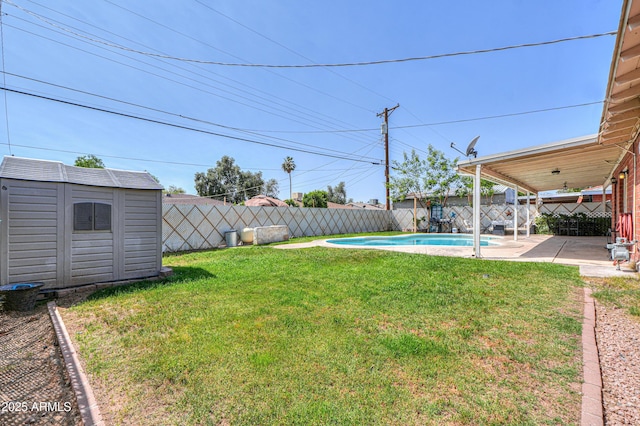 view of yard with a storage shed, a fenced in pool, a fenced backyard, an outbuilding, and a patio area
