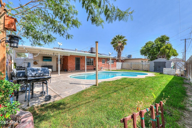 view of pool with a patio, a fenced backyard, a storage unit, a lawn, and an outdoor structure