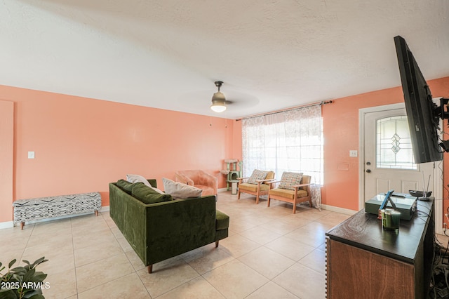 living area with a ceiling fan, light tile patterned floors, baseboards, and a textured ceiling