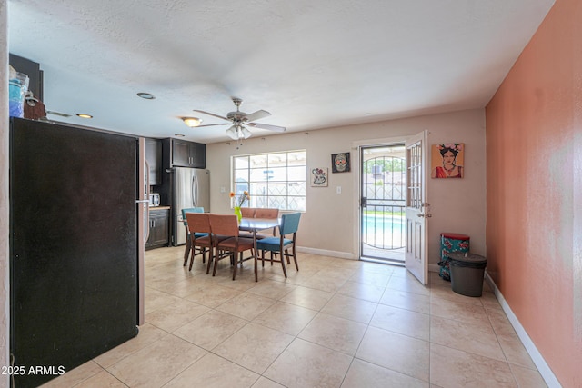dining room with baseboards, light tile patterned floors, a textured ceiling, and a ceiling fan
