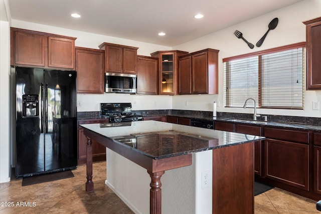 kitchen with sink, dark stone countertops, a breakfast bar, a kitchen island, and black appliances