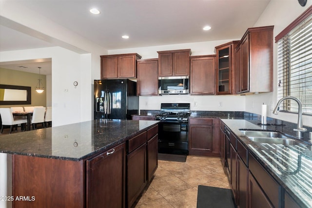 kitchen featuring a center island, black appliances, sink, light tile patterned floors, and decorative light fixtures