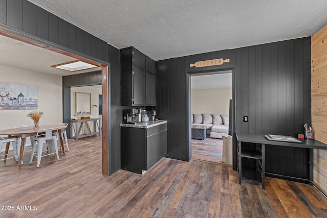 kitchen featuring light countertops, dark cabinetry, a textured ceiling, and wood finished floors