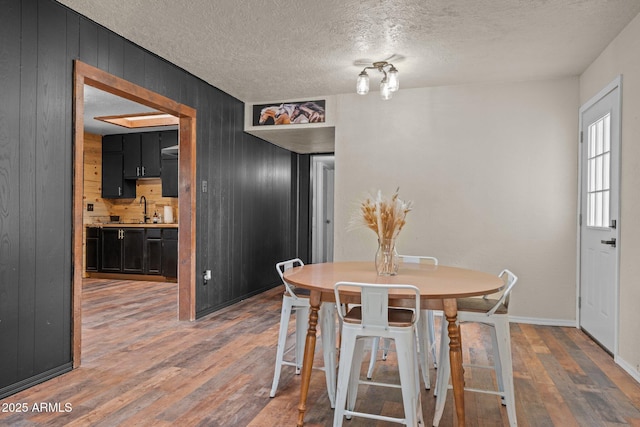 dining space with a textured ceiling, wood finished floors, and wood walls
