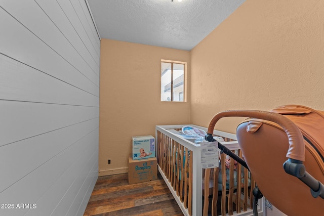 stairway with a textured wall, hardwood / wood-style flooring, and a textured ceiling