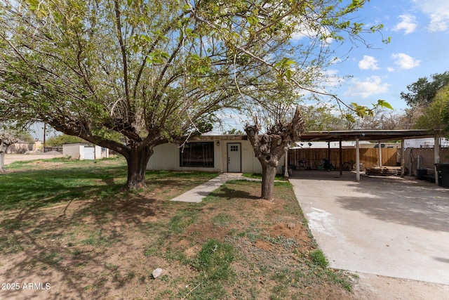 view of front of property with a front yard, a carport, fence, and concrete driveway
