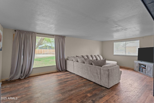 living area with dark wood-type flooring, a textured ceiling, and baseboards