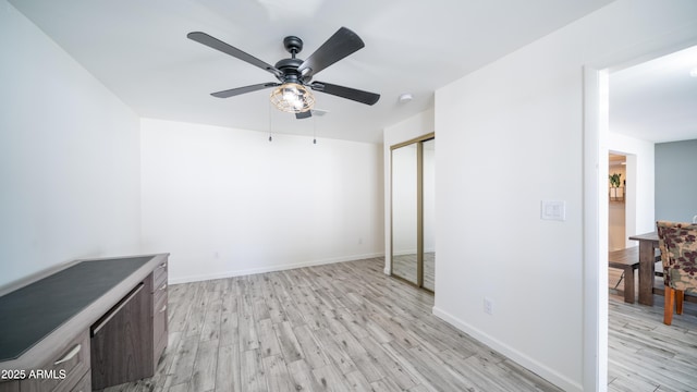 unfurnished bedroom featuring a closet, ceiling fan, baseboards, and light wood-style floors