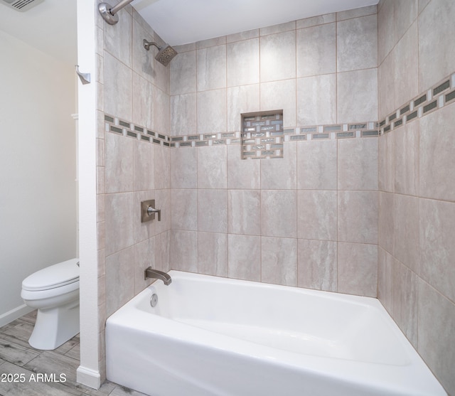 bathroom featuring toilet,  shower combination, and wood finished floors