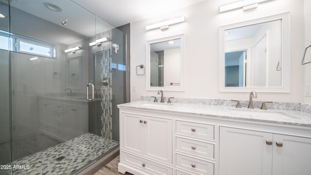 bathroom with double vanity, a stall shower, and a sink