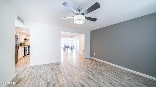 empty room featuring light wood finished floors, visible vents, ceiling fan, and baseboards