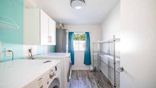 laundry room with baseboards, light wood-style flooring, cabinet space, water heater, and washing machine and dryer