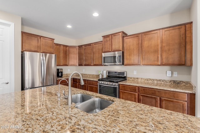 kitchen with sink, appliances with stainless steel finishes, and light stone counters