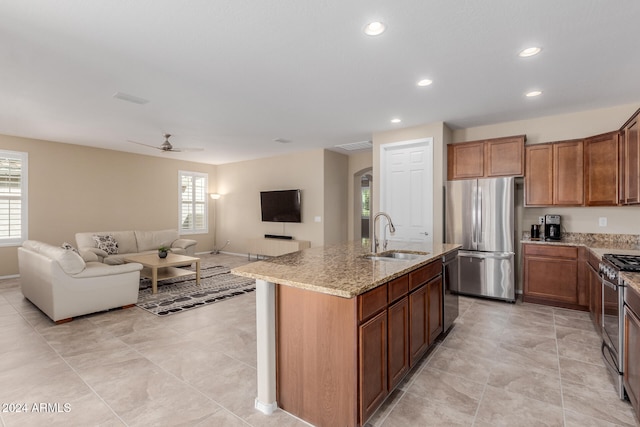 kitchen with sink, an island with sink, stainless steel appliances, and a healthy amount of sunlight