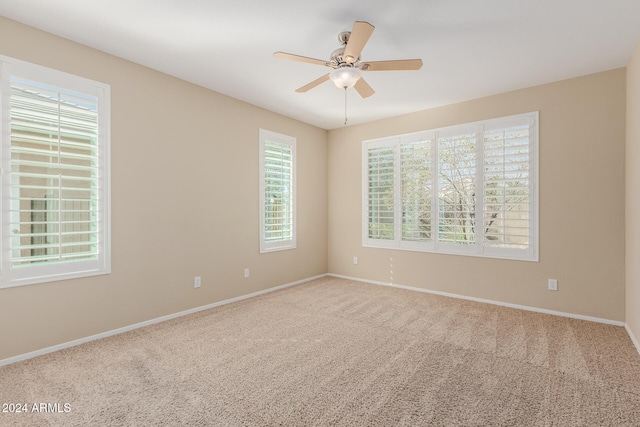 carpeted empty room featuring ceiling fan and plenty of natural light