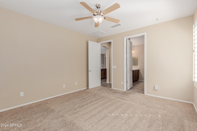 unfurnished bedroom featuring ensuite bathroom, light carpet, and ceiling fan