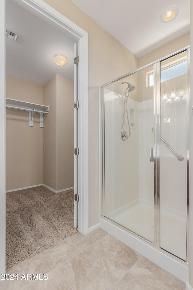 bathroom with a shower with shower door and tile patterned flooring