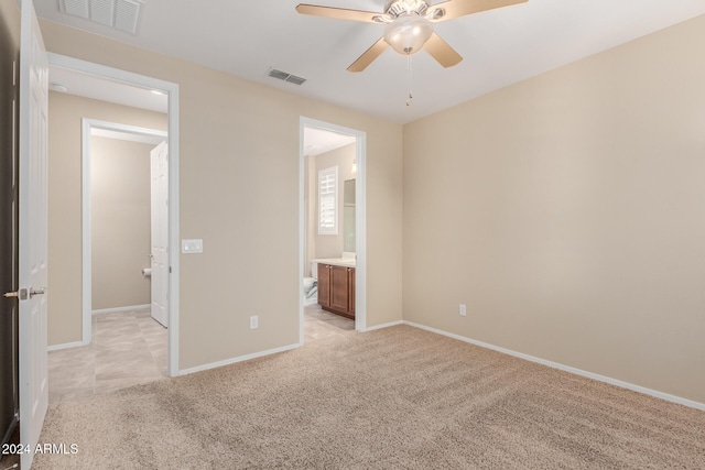 unfurnished bedroom featuring light carpet, ensuite bathroom, and ceiling fan