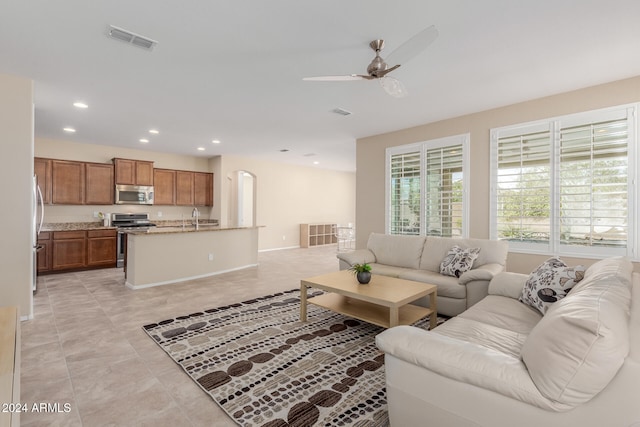 living room with sink, light tile patterned flooring, and ceiling fan