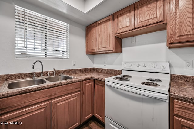 kitchen with dark countertops, brown cabinets, a sink, and white electric range oven