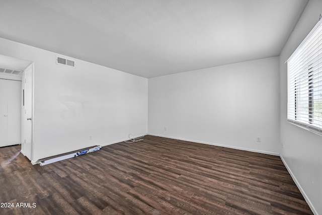 empty room featuring baseboards, visible vents, and wood finished floors