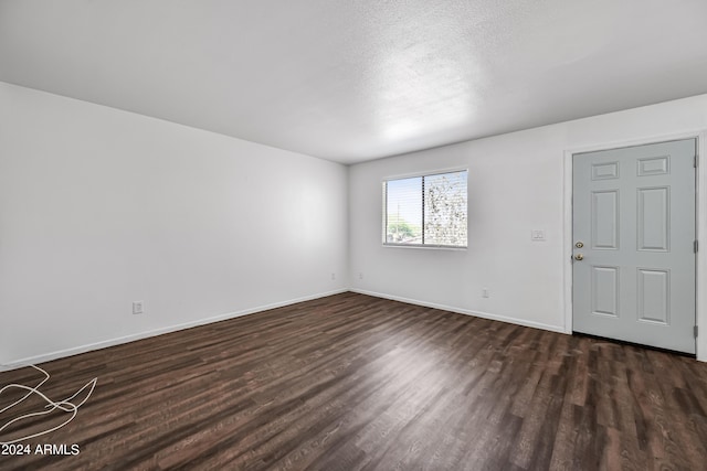 spare room featuring dark wood-style floors, a textured ceiling, and baseboards